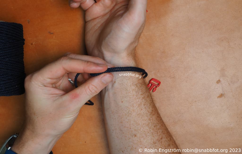 Ett svart snöre lindat runt en handled