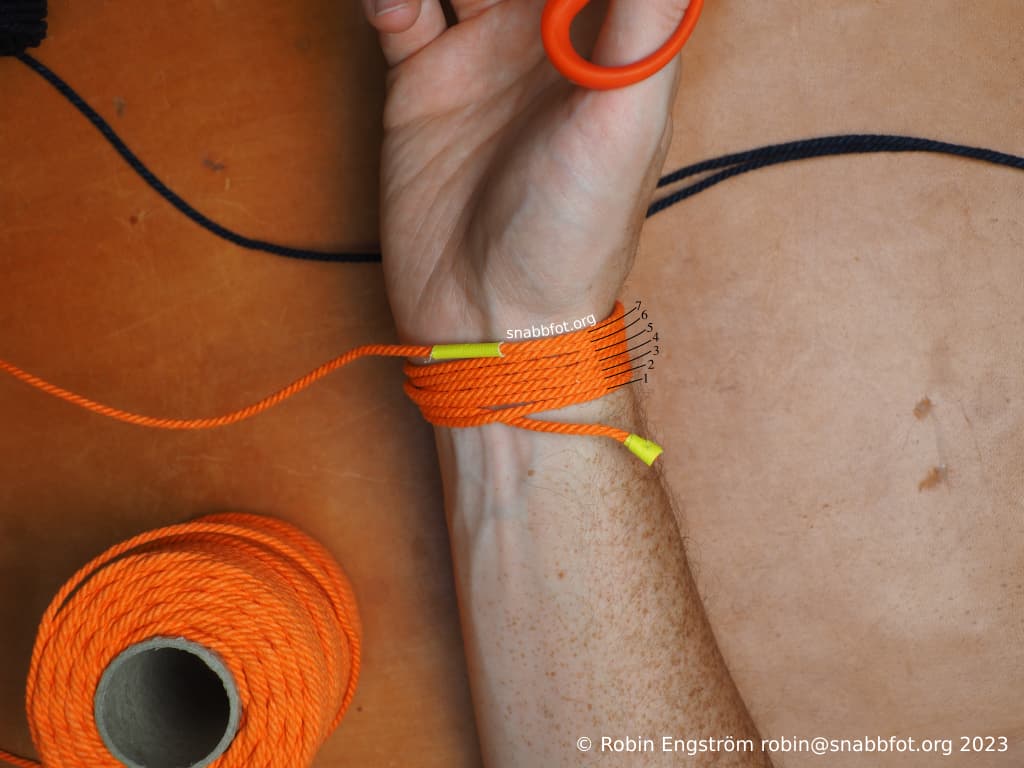 Ett orange snöre lindat runt en handled sju ggr